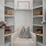 Model walk in closet at our apartments in Addison, featuring hangers, shelving, and a cushioned chair.