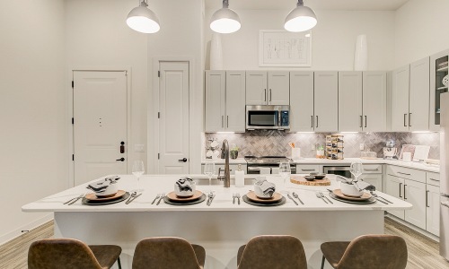 Model kitchen at our apartments in Addison, featuring a kitchen island with counter seating and table settings.